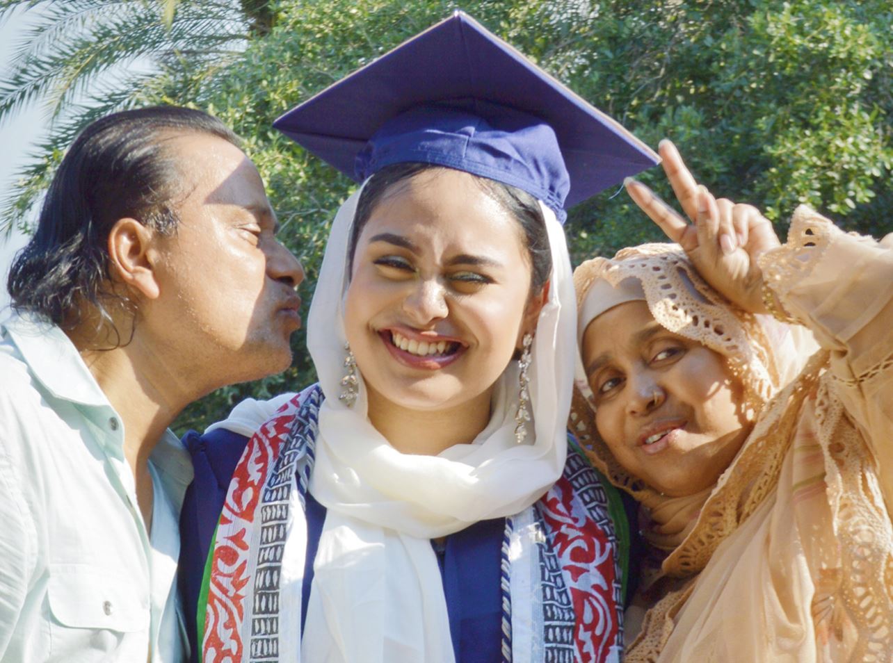 Mother and father taking picture with their daughter on graduation day