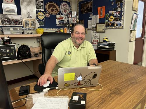 Mr. Davis sitting behind a desk in his classroom