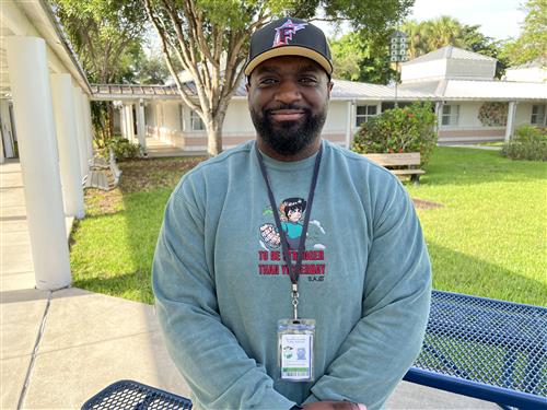 Mr. Andy standing outside in the courtyard wearing a Florida Marlins cap