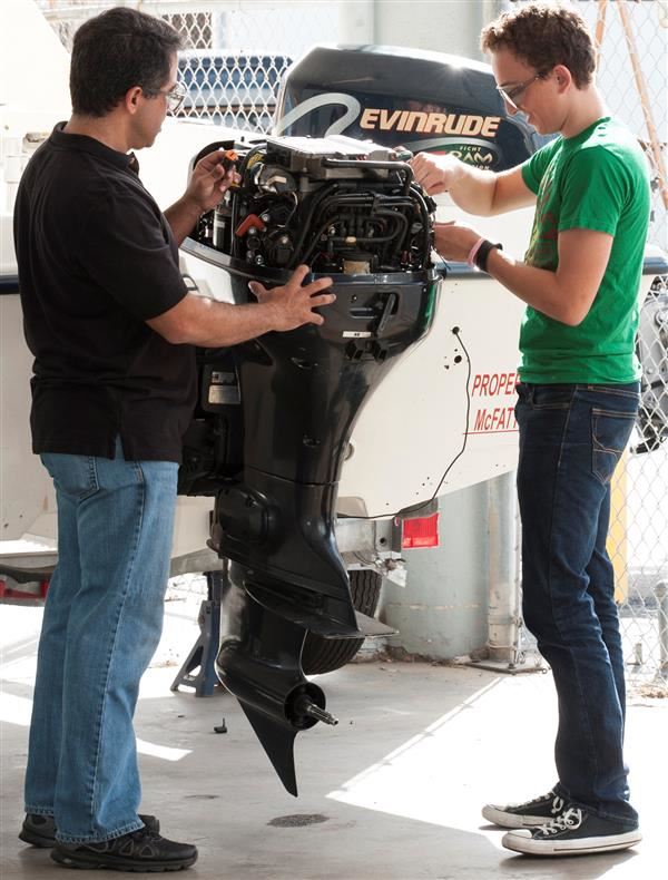 Two students working on a boat motor in the marine service technology class Two students working on a boat motor in the marine service technology class