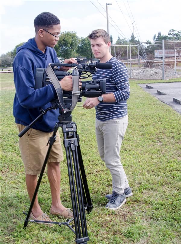 Two Students Working A Camera In A field for TV production Class Two Students Working A Camera In A field for TV production Class
