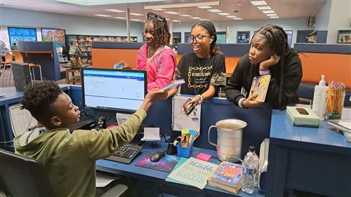 student checking out books to other students